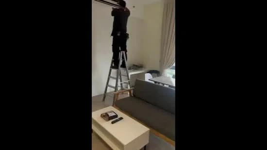 Living features: grey fabric sofa, white coffee table, TV remote control, magazine on coffee table, floor lamp, curtains, wall-mounted TV bracket, carpeted flooring, light-colored walls; style: modern.