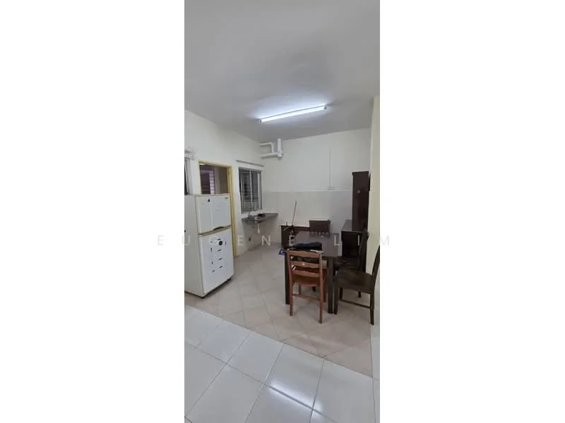 Room features: white painted walls, tile flooring, fluorescent ceiling light, window with grid, dining table with chairs, white cabinet, wooden cabinet, kitchen countertop, sink, wall-mounted pipe, open layout.
