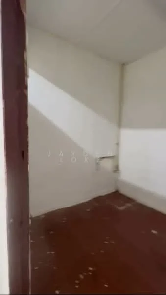 Room features: white painted walls, brown flooring, corner with no visible windows, minimal natural light.