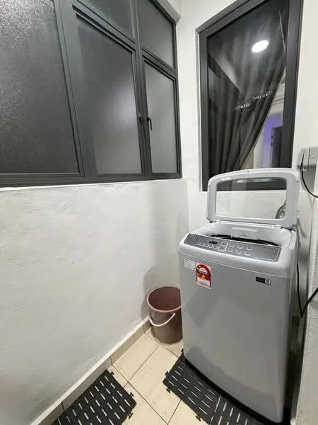 Laundry features: top-load washing machine in grey, white painted walls, tile flooring, black rubber mat, window with black frame, curtain, plastic bucket.