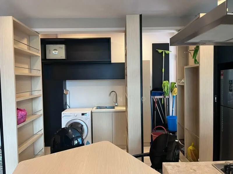 Kitchen features: light wood cabinetry, black open shelving, single-bowl stainless-steel sink, chrome faucet, built-in washing machine, countertop with integrated storage, refrigerator, cleaning supplies visible, broom and mop, open layout, modern design; style: modern.