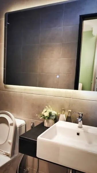Bathroom features: white ceramic toilet, single-sink vanity with black countertop, chrome basin mixer faucet, framed mirror, grey tiled walls, decorative vase with flowers, two decorative bottles, wall-mounted light above mirror; style: modern.