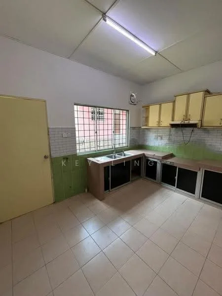 Kitchen features: green tiled walls, white painted walls, light-colored cabinetry with handles, countertop with storage underneath, single-bowl stainless-steel sink, window with metal grille, tile flooring, fluorescent ceiling lights.