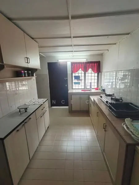 Kitchen features: light wood cabinetry, white tiled backsplash, grey countertop, single-bowl stainless-steel sink, chrome pull-down faucet, built-in stove, window with red curtains, floor tiles, door leading outside.