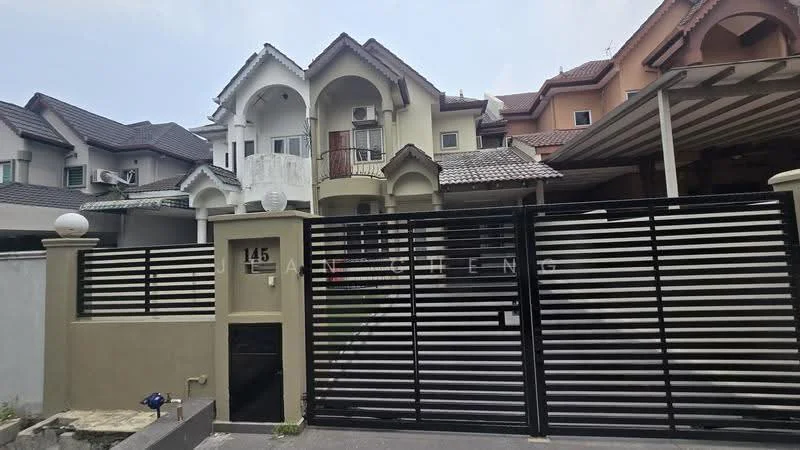 Exterior type: linked terrace house; features: black metal gate, white painted facade, grey stone cladding, two-storey structure, gabled roof, balcony on upper floor, decorative arches, covered car porch, manicured front garden, multiple air conditioning units visible, security lights, intercom panel at entrance; style: modern.