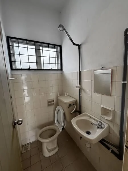 Bathroom features: white tiled walls, cream tiled flooring, one-piece toilet, chrome basin mixer faucet, small sink, framed mirror, shower head, window with metal grille.