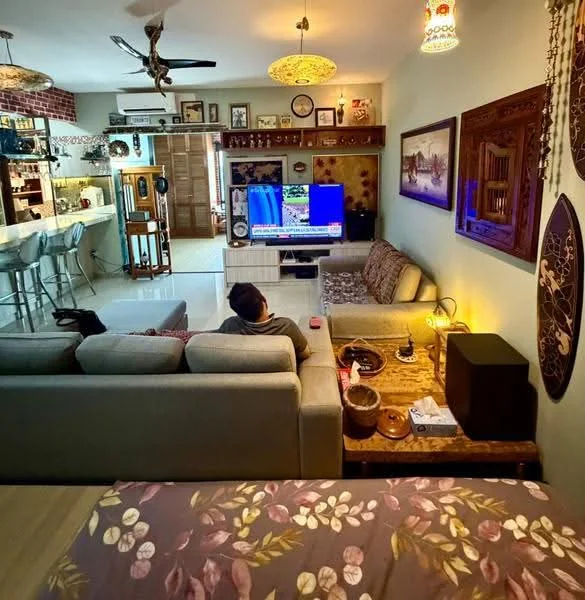 Living features: 3-seater fabric sofa in grey, 2-seater fabric sofa in beige, coffee table, wall-mounted TV, entertainment unit, area rug, ceiling fan, decorative wall art, wooden shelving, bar counter with stools, glass sliding door, recessed lighting; style: modern. Room features: bed with floral bedding, decorative wall panel, wooden cabinet, table lamp.