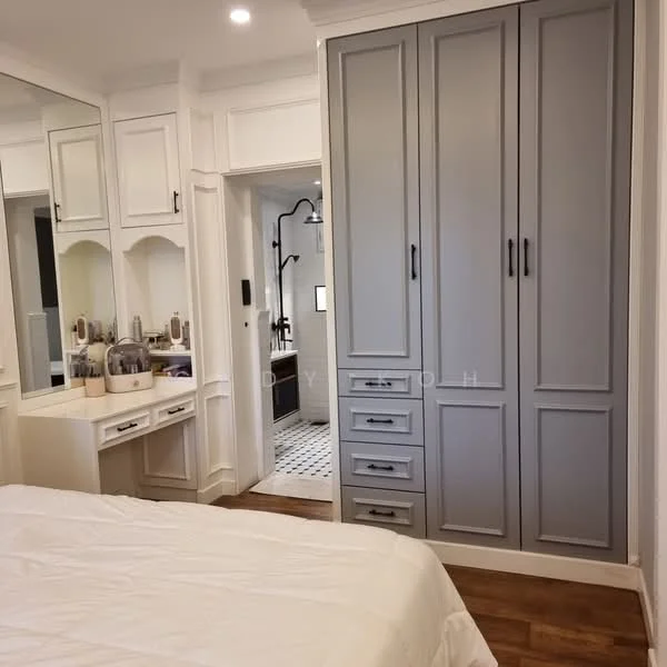 Bedroom features: grey built-in wardrobe with multiple drawers, white painted walls, wooden flooring, vanity area with mirror, recessed lighting, bed with white bedding, decorative wall paneling, doorway leading to bathroom; style: modern.