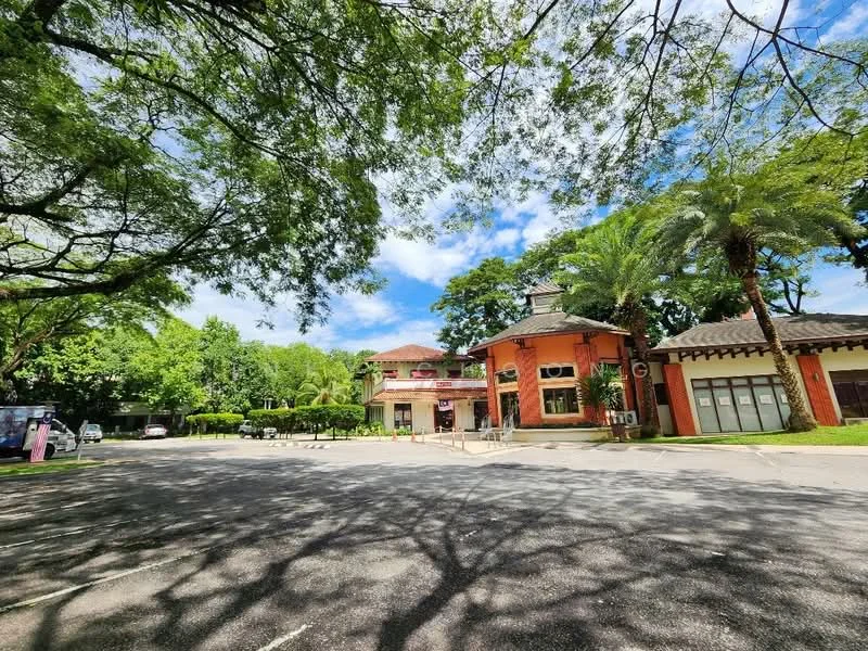 Exterior type: clubhouse; features: red brick facade, flat roof, surrounded by mature greenery, paved driveway, large windows, outdoor seating area, landscaped garden, palm trees, open-air parking lot; style: tropical-modern.
