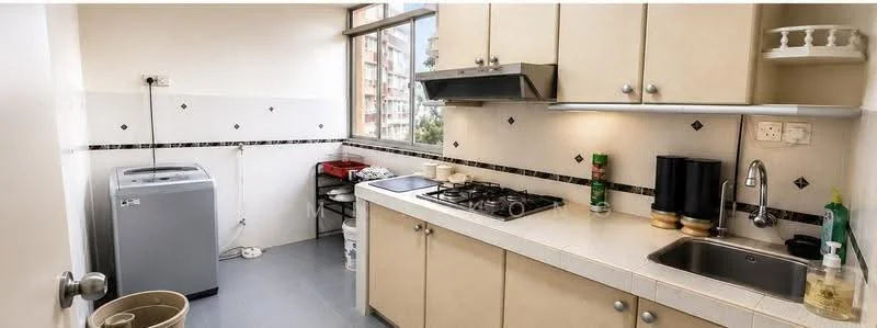 Kitchen features: cream cabinetry, white tiled backsplash, stainless-steel sink, chrome pull-down faucet, 4-burner gas hob, built-in range hood, washing machine, countertop with white surface, window with city view, tile flooring, garbage bin, kitchen utensils on countertop; style: modern; view: city.