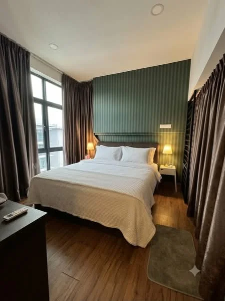 Bedroom features: king-size bed with white bedding, upholstered headboard, two bedside lamps, wooden flooring, green accent wall with vertical stripes, floor-to-ceiling windows, sheer curtains, dark brown curtains, nightstand, decorative area rug; style: modern.