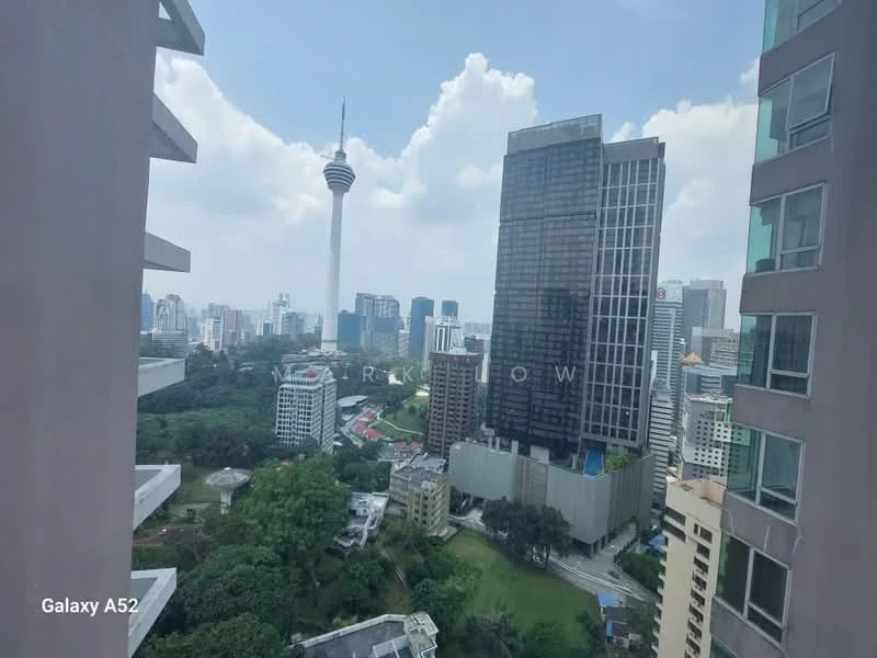 Exterior type: high-rise condominium; features: city skyline view, surrounded by greenery, modern glass facade, tall buildings in the background, KL Tower visible, urban landscape, mixed-use development; style: modern.