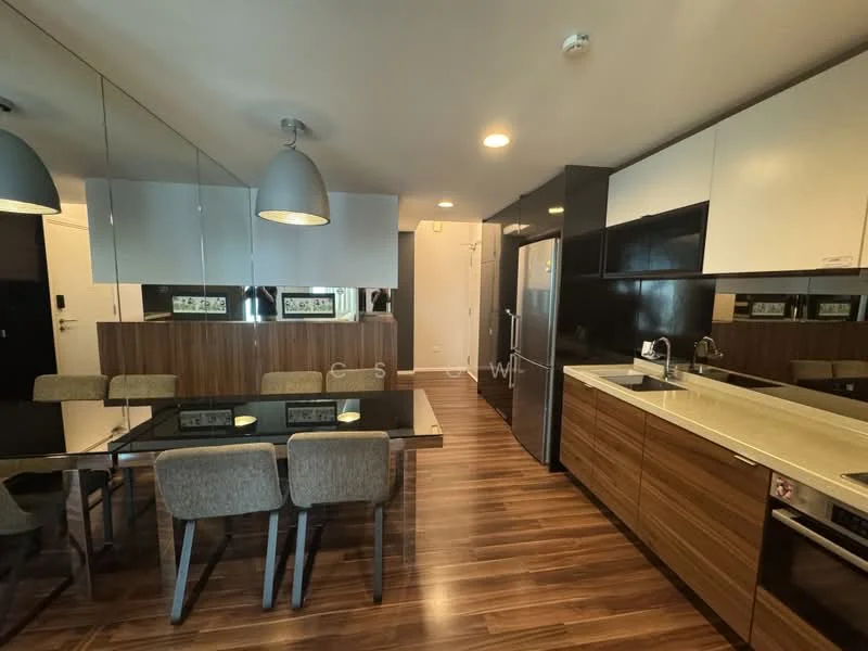 Kitchen features: dark wood cabinetry, white upper cabinets, stainless-steel refrigerator, built-in oven, 4-burner gas hob, single-bowl stainless-steel sink, chrome pull-down faucet, black countertop, mirrored wall, dining table with 6 upholstered chairs, pendant lighting, wood laminate flooring; style: modern.