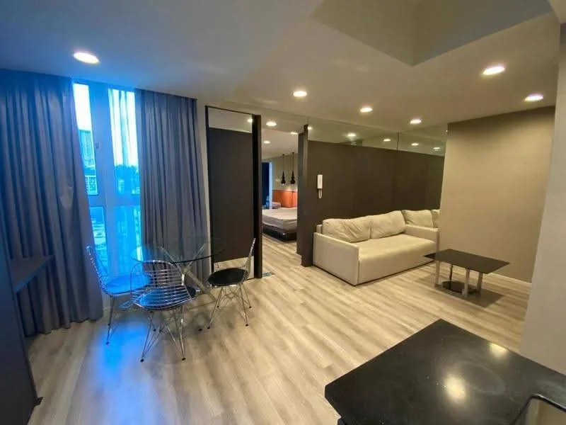 Living features: light grey fabric sofa, glass coffee table, 4-seater dining table with transparent chairs, laminate flooring, recessed downlights, floor-to-ceiling windows with sheer curtains, mirrored wall, neutral painted walls; style: modern.