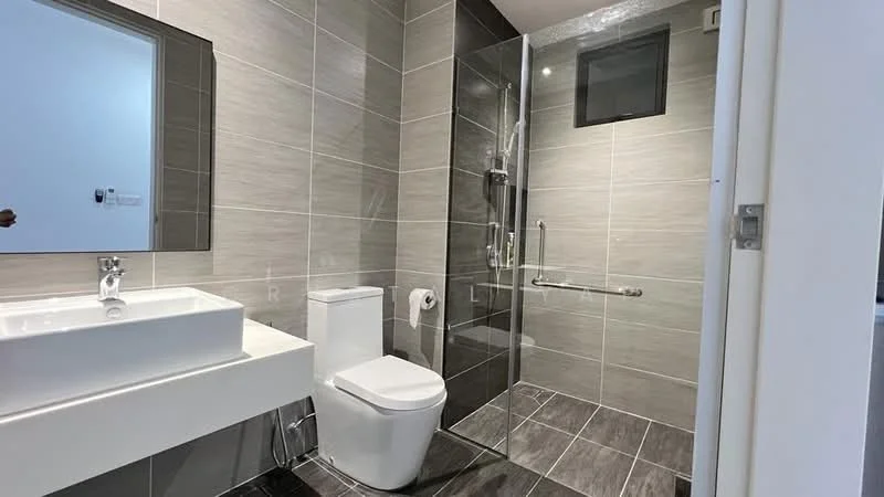 Bathroom features: grey ceramic tile flooring, grey wall tiles, white wall-mounted sink, chrome basin mixer faucet, white one-piece toilet, walk-in shower with glass enclosure, rain shower head, handheld shower, grab bars, mirror above sink, toilet paper holder, small window for natural light; style: modern.