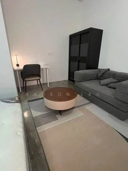 Living features: grey fabric sofa, round coffee table with wooden top, area rug with geometric pattern, concrete flooring, white painted walls, desk with chair, table lamp, black wardrobe with sliding doors; style: modern.