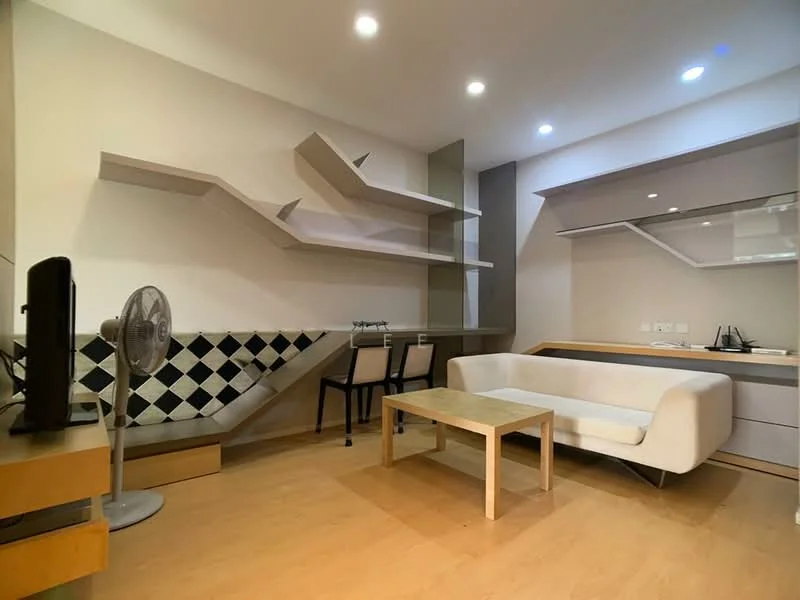 Living features: light wood flooring, white walls, modern shelving unit with geometric design, black and white patterned accent wall, sofa in white fabric, wooden coffee table, 2 dining chairs, wall-mounted TV, ceiling lights, standing fan; style: modern.