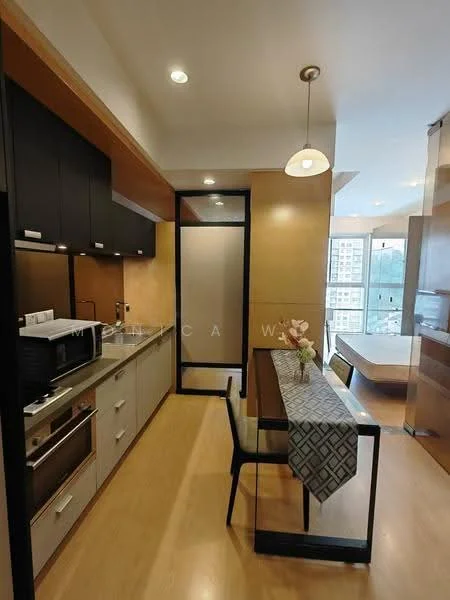 Kitchen features: black cabinetry, stainless-steel sink, chrome pull-down faucet, built-in microwave, freestanding range oven, ceramic tile backsplash, countertop with wood finish, recessed downlights, wooden flooring, dining table with patterned table runner, black dining chair, open layout to living area; style: modern; view: city. Room features: large window with city view, bed visible in background.