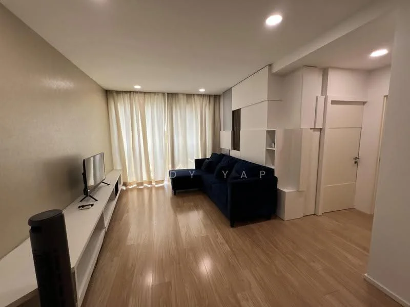 Living features: light wood laminate flooring, white painted walls, floor-to-ceiling windows with sheer curtains, L-shape sectional sofa in navy blue, white TV console, wall-mounted TV, built-in shelving unit, recessed downlights; style: modern.