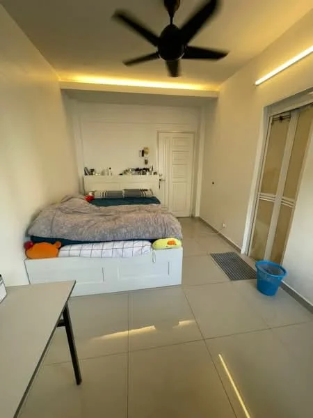 Bedroom features: queen-size bed with grey bedding, white bed frame with storage, ceiling fan, wall-mounted mirror, white painted walls, tile flooring, sliding glass door, small blue trash bin, table with legs, decorative items on the table, natural light from window; style: modern.