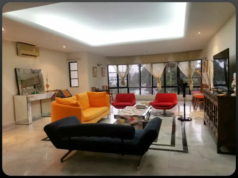 Living features: sofa in navy blue fabric, 3-seater orange fabric sofa, 2-seater red fabric sofa, coffee table with glass top, area rug with geometric pattern, TV console with wooden finish, wall-mounted TV, floor-to-ceiling windows, sheer curtains, recessed LED downlights, air conditioning unit, decorative wall art, wooden side table, dining area visible in background; style: modern; view: garden.