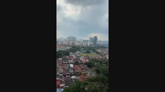 Exterior type: high-rise condominium; features: city skyline view, surrounded by urban landscape, visible residential buildings, green open space, cloudy sky; style: modern.