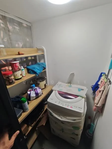 Laundry features: white painted walls, shelving unit with wooden shelves, various storage containers, stacked laundry basket, washing machine, cleaning supplies, flooring not visible, ceiling light fixture.