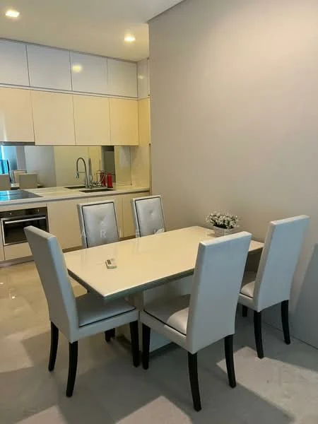 Dining features: white dining table, 4 upholstered dining chairs in white, kitchen cabinetry with light beige finish, stainless-steel sink, chrome pull-down faucet, built-in oven, microwave, recessed downlights, marble tile flooring, decorative flower arrangement; style: modern. Kitchen features: white cabinetry, stainless-steel appliances, open-plan layout, countertop with integrated sink; style: modern.