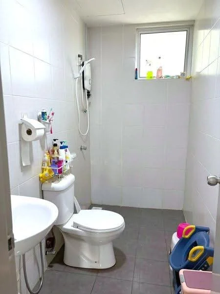 Bathroom features: white tiled walls, grey ceramic tile flooring, single-sink vanity, one-piece toilet, shower with wall-mounted shower head, window for natural light, various toiletries on shelves, toilet paper holder.