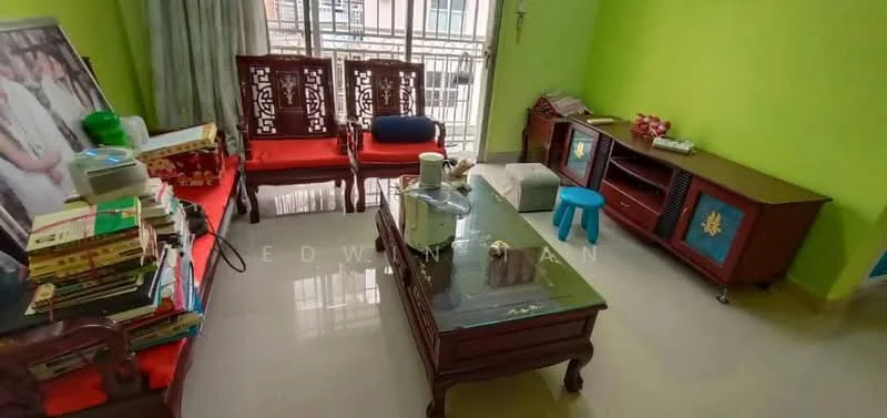 Living features: green painted walls, glossy tile flooring, wooden coffee table, wooden sideboard, 2 wooden chairs with cushions, blue plastic stool, books stacked on side table, large framed photo, curtains, window with grille, decorative wall hanging; style: traditional.
