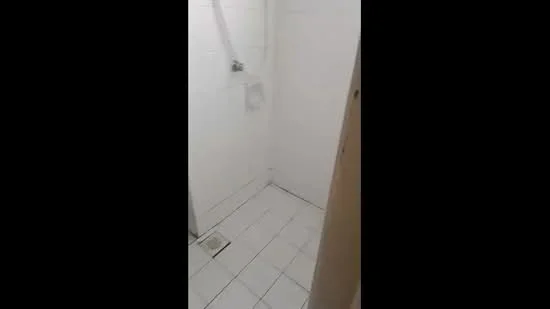 Bathroom features: white tiled walls, white tiled flooring, shower area with wall-mounted showerhead, drain in floor, minimalist design, no visible storage, bright lighting; style: modern.