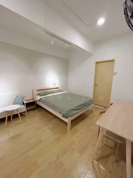 Bedroom features: queen-size bed with green bedding, light wood bed frame, wooden flooring, white painted walls, track lighting, wall-mounted light fixture, small bedside table, chair with light wood legs, desk with light wood legs, door to hallway; style: minimalist.