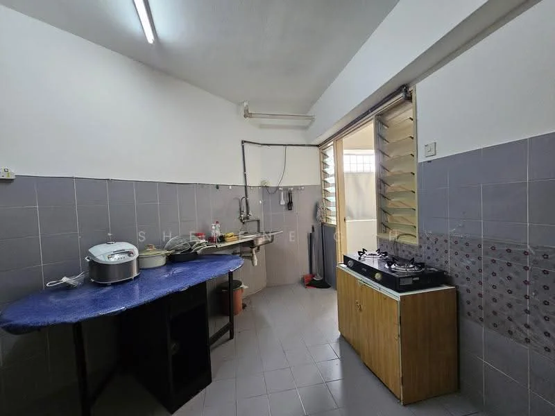 Kitchen features: grey tiled walls, light grey tiled flooring, wooden cabinetry, gas stove, cooking pot on stove, rice cooker on counter, open window with louvered shutters, blue tablecloth on table, sink with faucet, wall-mounted shelves.