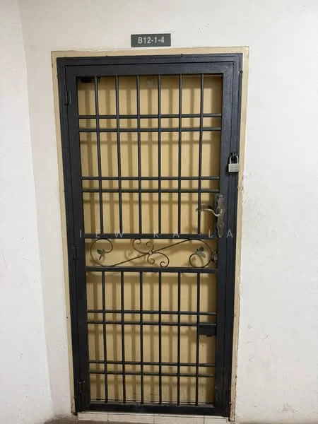 Room features: metal security door, grid pattern on door, padlock on door, number plate above door with text 'B121-4', neutral wall colour, plain wall surface.
