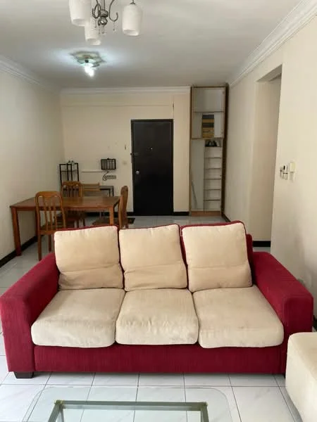 Living features: 3-seater fabric sofa in red, coffee table with glass top, white painted walls, tile flooring, ceiling light fixture, door leading to hallway, wall-mounted shelving unit, dining table with 4 chairs in background; style: modern.