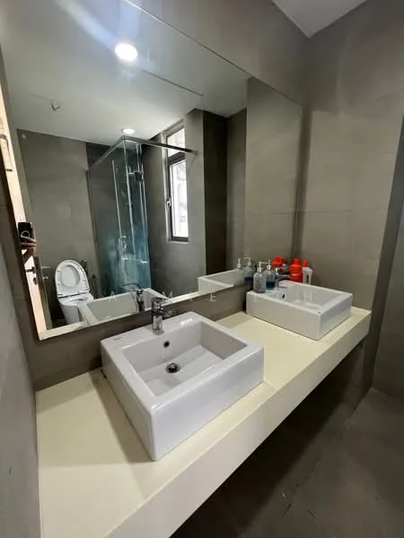 Bathroom features: wall-mounted sink with square basin, chrome basin mixer faucet, large wall mirror, glass shower enclosure, toilet, grey tiled walls, grey tiled flooring, white countertop, bathroom accessories on countertop; style: modern.