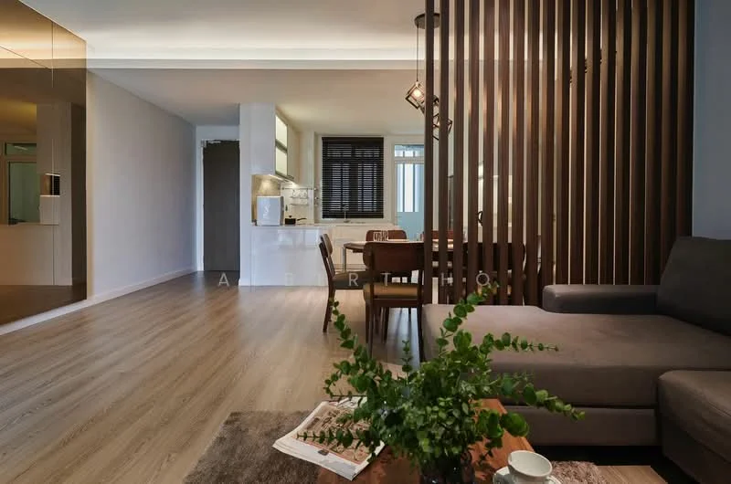 Living features: grey fabric sofa, wooden coffee table, area rug, wooden dining chairs, wooden dining table, laminate flooring, recessed ceiling lights, decorative plant, partition wall with vertical slats, large windows with black frames, wall-mounted light fixture; style: modern. Kitchen features: open kitchen layout, white cabinetry, stainless-steel appliances, kitchen island, black countertops; style: modern.
