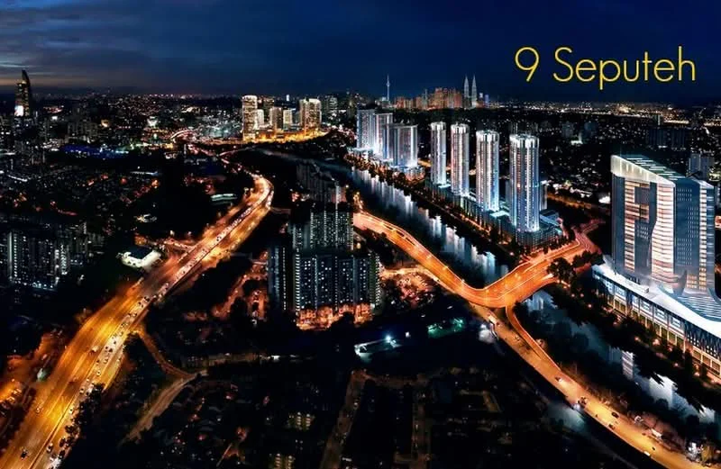 Exterior type: high-rise condominium; features: city skyline view, illuminated buildings, riverfront location, surrounding roadways, nighttime lighting, modern architectural design, green landscaping, proximity to urban amenities; style: modern.