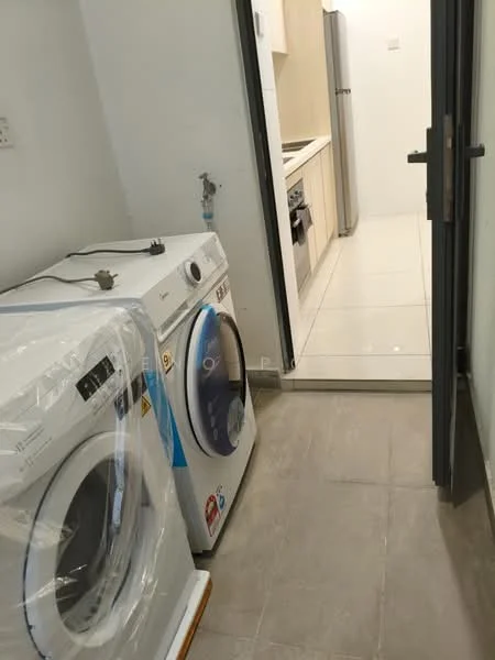 Laundry features: 2 front-load washing machines, grey tiled flooring, white walls, glass door leading to kitchen, plumbing connection, cabinets in light wood finish, countertop in light colour, kitchen appliances visible in background; style: modern.