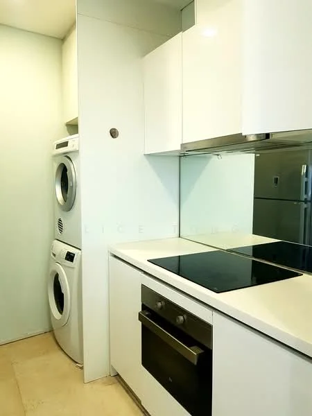 Kitchen features: white cabinetry, built-in oven, induction cooktop, white quartz countertop, mirror backsplash, stacked washer and dryer, light beige tile flooring, recessed downlights; style: modern.