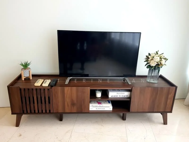 Living features: wooden TV console with slatted design, flat-screen TV, decorative plant in ceramic pot, vase with flowers, remote controls, books stacked on console, candle on console, marble flooring; style: modern.