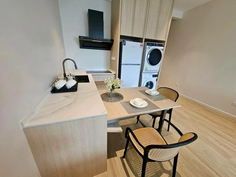 Kitchen features: white marble countertop, light wood cabinetry, stainless-steel sink, chrome pull-down faucet, built-in oven, freestanding fridge, front-load washing machine, 2 dining chairs, dining table, decorative vase with flowers, ceramic plates; style: modern.