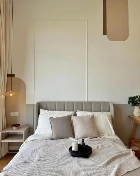 Bedroom features: queen-size bed with upholstered headboard, white bedding with decorative pillows, nightstand with drawer, table lamp with pendant light, decorative wall art, wooden side table, plant in ceramic pot, light-colored walls, wooden flooring; style: modern.