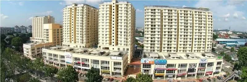 Exterior type: mid-rise condominium; features: multiple-storey buildings, commercial units on ground floor, balconies on upper floors, glass windows, cream painted facade, surrounded by greenery, open plaza area, urban context, visible parking area; style: modern.