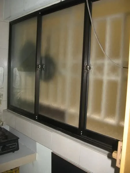 Kitchen features: black framed window, frosted glass, kitchen countertop, gas stove, tile backsplash, wall-mounted cabinet, cooking utensils visible.