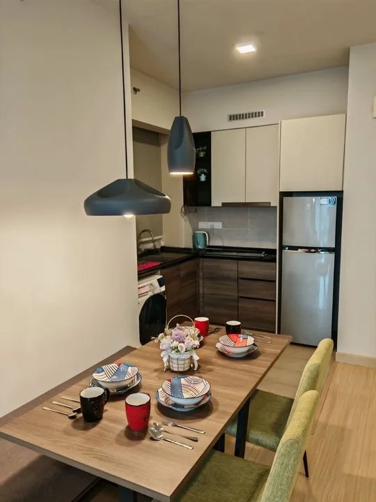 Kitchen features: black and white cabinetry, stainless-steel fridge, built-in oven, ceramic cooktop, kitchen island with dining table, hanging pendant lights, wooden flooring, dishwasher, decorative table setting with plates and cups, kettle on countertop; style: modern.