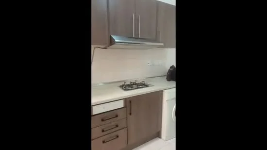 Kitchen features: brown cabinetry, stainless-steel range hood, 4-burner gas hob, white countertop, built-in oven, washing machine, tile backsplash, light-colored tile flooring; style: modern.