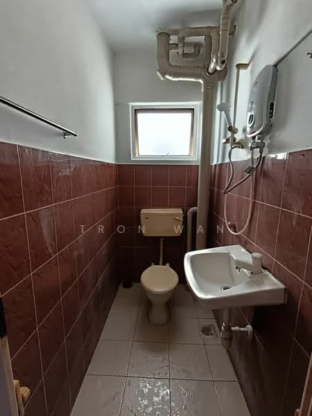 Bathroom features: brown tiled walls, white ceramic floor tiles, single-sink vanity with faucet, toilet, window, water heater, exposed plumbing, towel rack.