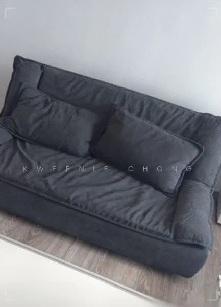 Living features: 3-seater fabric sofa in dark grey, two decorative cushions, wooden flooring, minimalist side table, neutral wall color; style: modern.