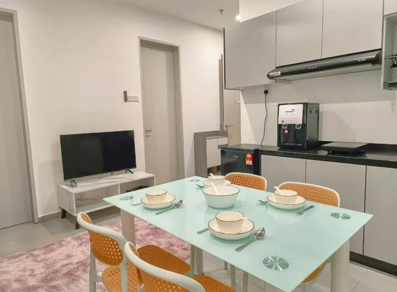 Dining features: glass dining table, 4 dining chairs with orange seats, white walls, grey cabinetry, black countertop, stainless-steel appliances, built-in coffee machine, flat-screen TV, light grey rug, refrigerator, kitchenette area; style: modern.